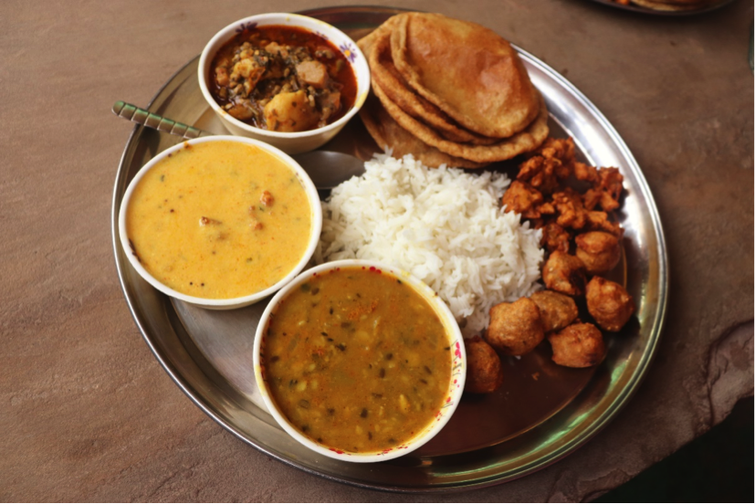 « Rajasthani Thali » – Bundi. Sortiment von 3 Masala-Gewürzmischungen begleitet von Reis, Chapatis und süssen frittierten Kuchen aus Kokosnuss (rechts auf dem Teller).